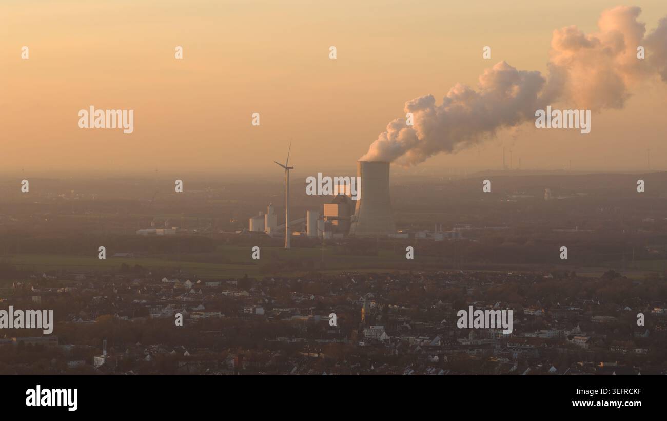 Impianto a carbone che inquinano l'atmosfera con fumo vicino alla turbina eolica Foto Stock