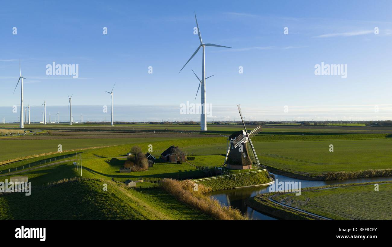 Mulino a vento tradizionale e turbine eoliche moderne simboleggiano la transizione energetica Foto Stock