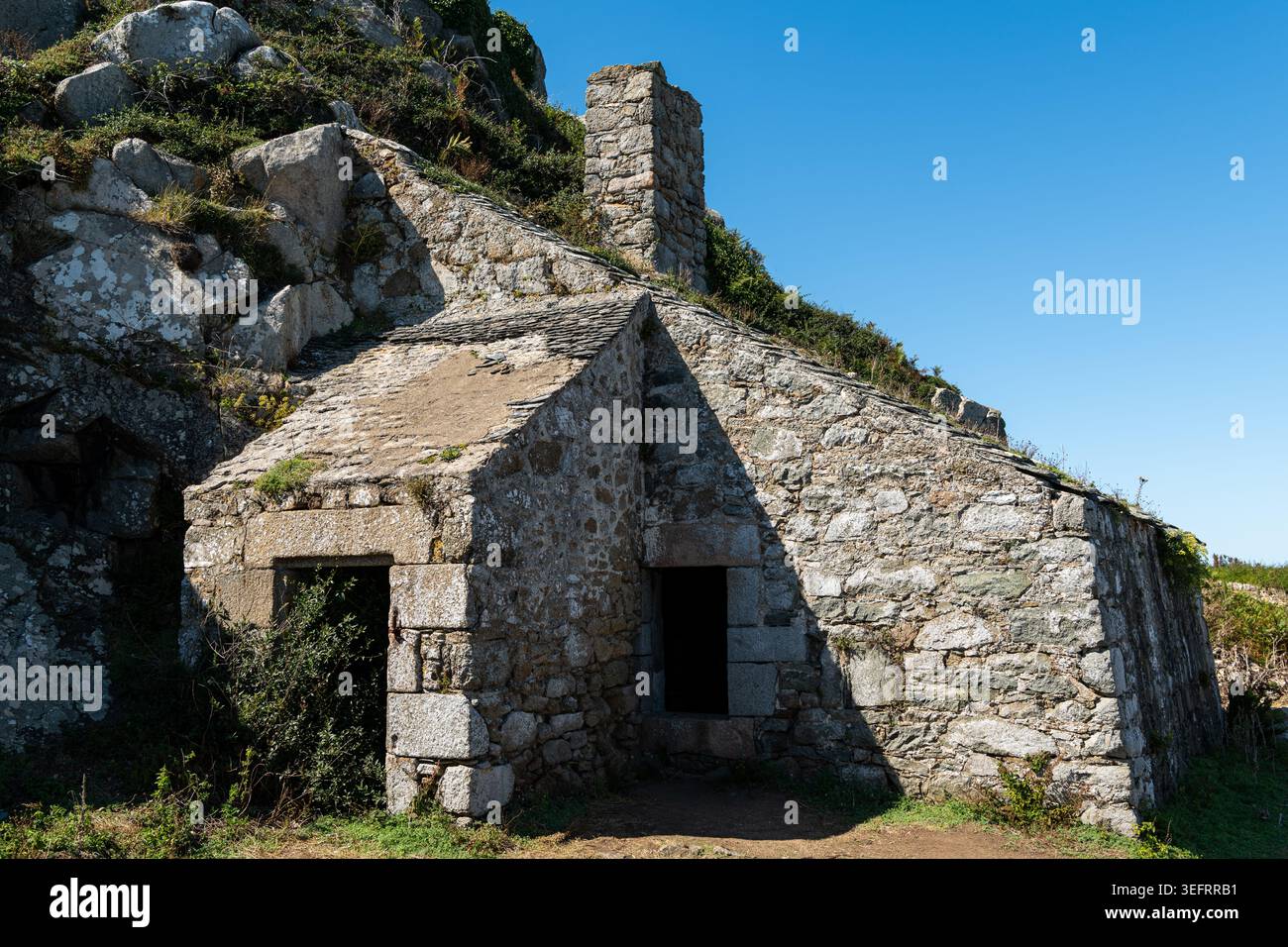 Perros-Guirec, Francia - 31 agosto 2020: Vista frontale del rifugio ufficiale della dogana bretone in pietra restaurata Maison du Douanier con due porte, camino, ardesia Foto Stock