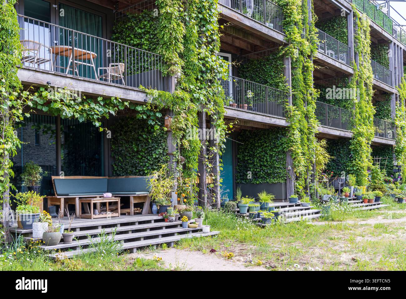 Moderno edificio di appartamenti verde con giardini verticali a cascata, spaziosi balconi ed elementi strutturali in legno in una tranquilla area suburbana di ed Foto Stock