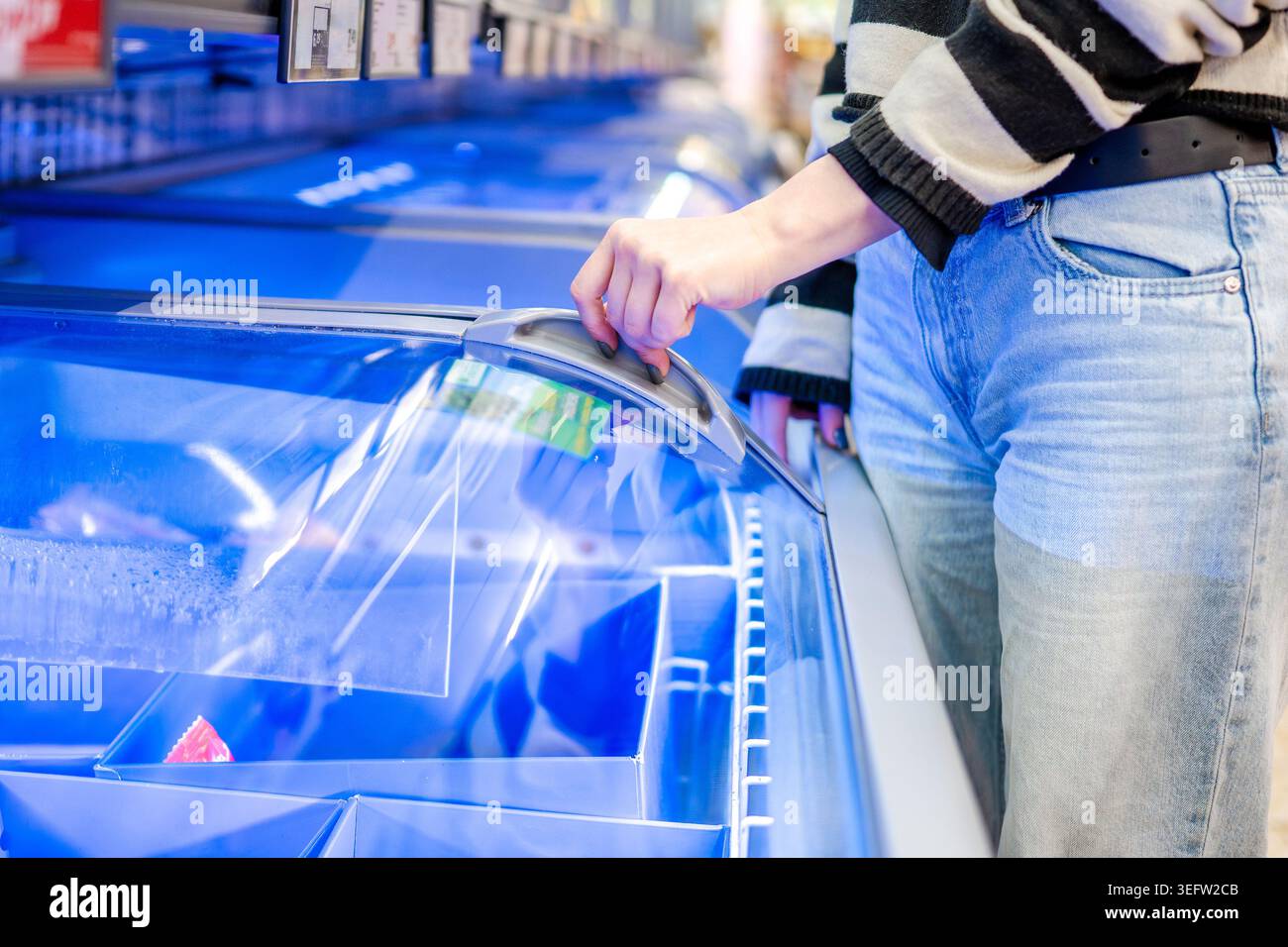Donna che apre il congelatore nelle mani del supermercato primo piano Foto Stock