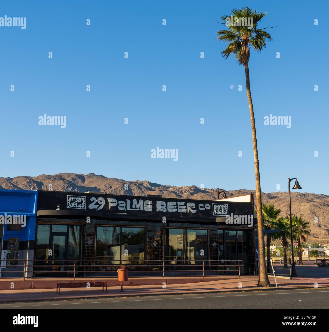 Il birrificio 29 Palms Beer Co. Si trova nel centro di Twentynine Palms, California, incorniciato da un'alta palma e dalle aspre montagne del deserto del Mojave Foto Stock