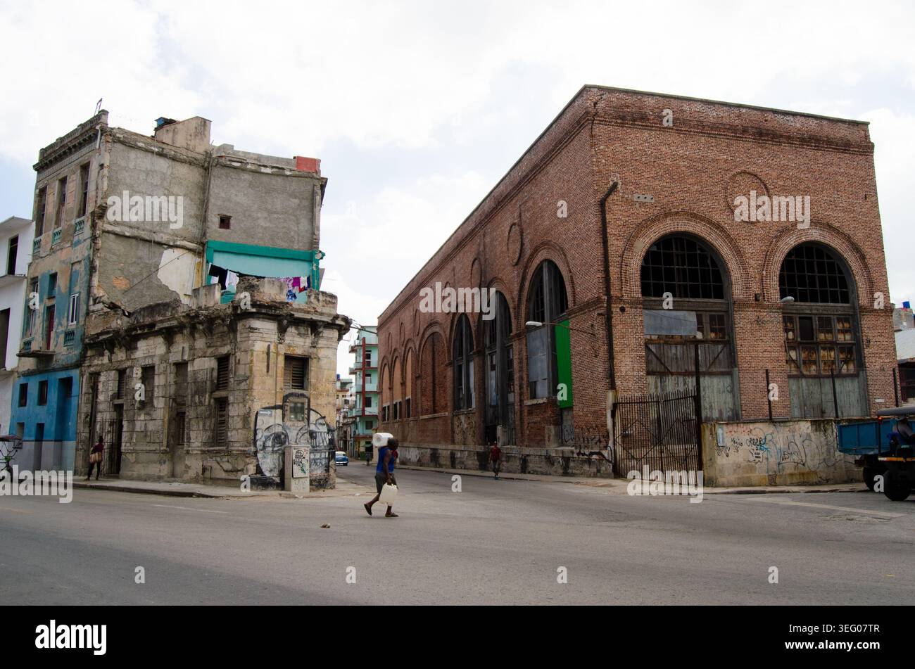Edifici storici e facciate fatiscenti fiancheggiano le strade di l'Avana, con una persona che passa accanto Foto Stock