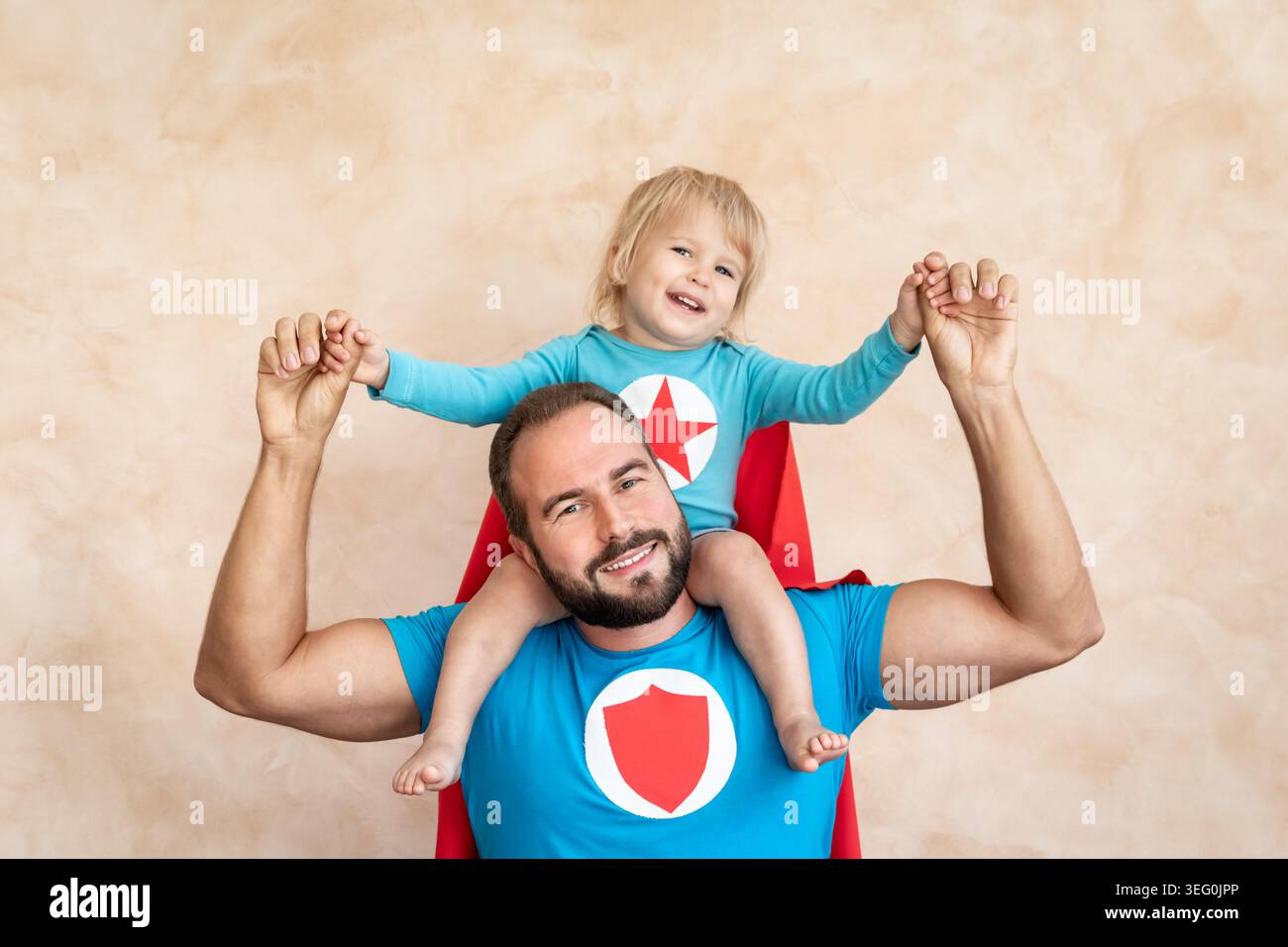Un uomo e un bambino super eroe a casa. Padre e figlio supereroi che si divertono insieme. Concetto di vacanza in famiglia. Felice giornata di papà Foto Stock