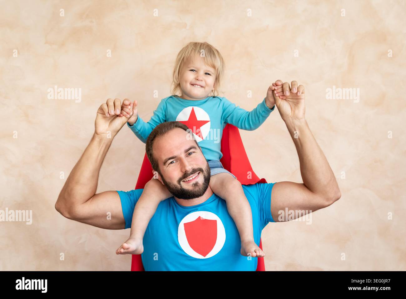 Un uomo e un bambino super eroe a casa. Padre e figlio supereroi che si divertono insieme. Concetto di vacanza in famiglia. Felice giornata di papà Foto Stock