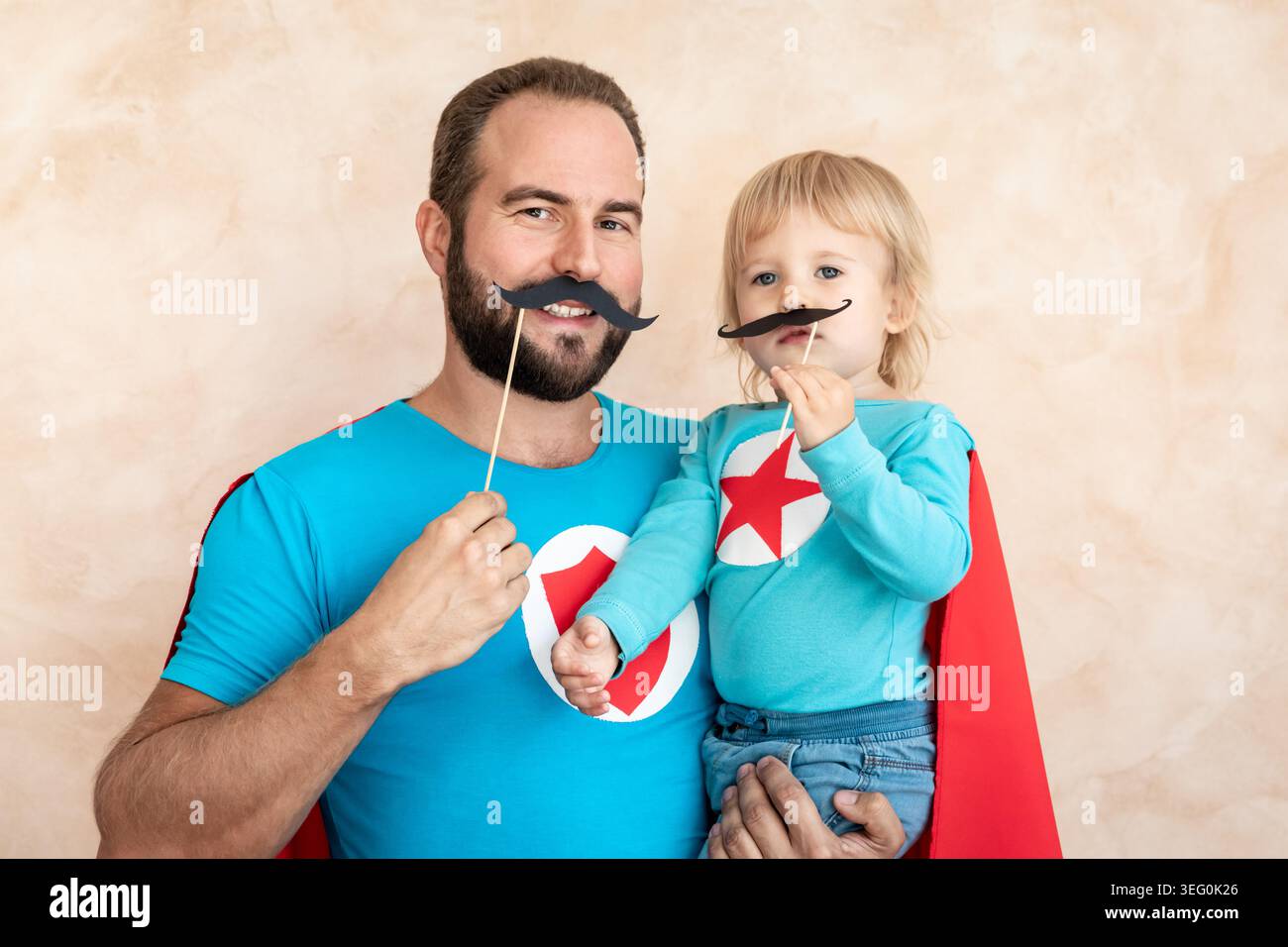 Un uomo e un bambino super eroe a casa. Padre e figlio supereroi che si divertono insieme. Concetto di vacanza in famiglia. Felice giornata di papà Foto Stock