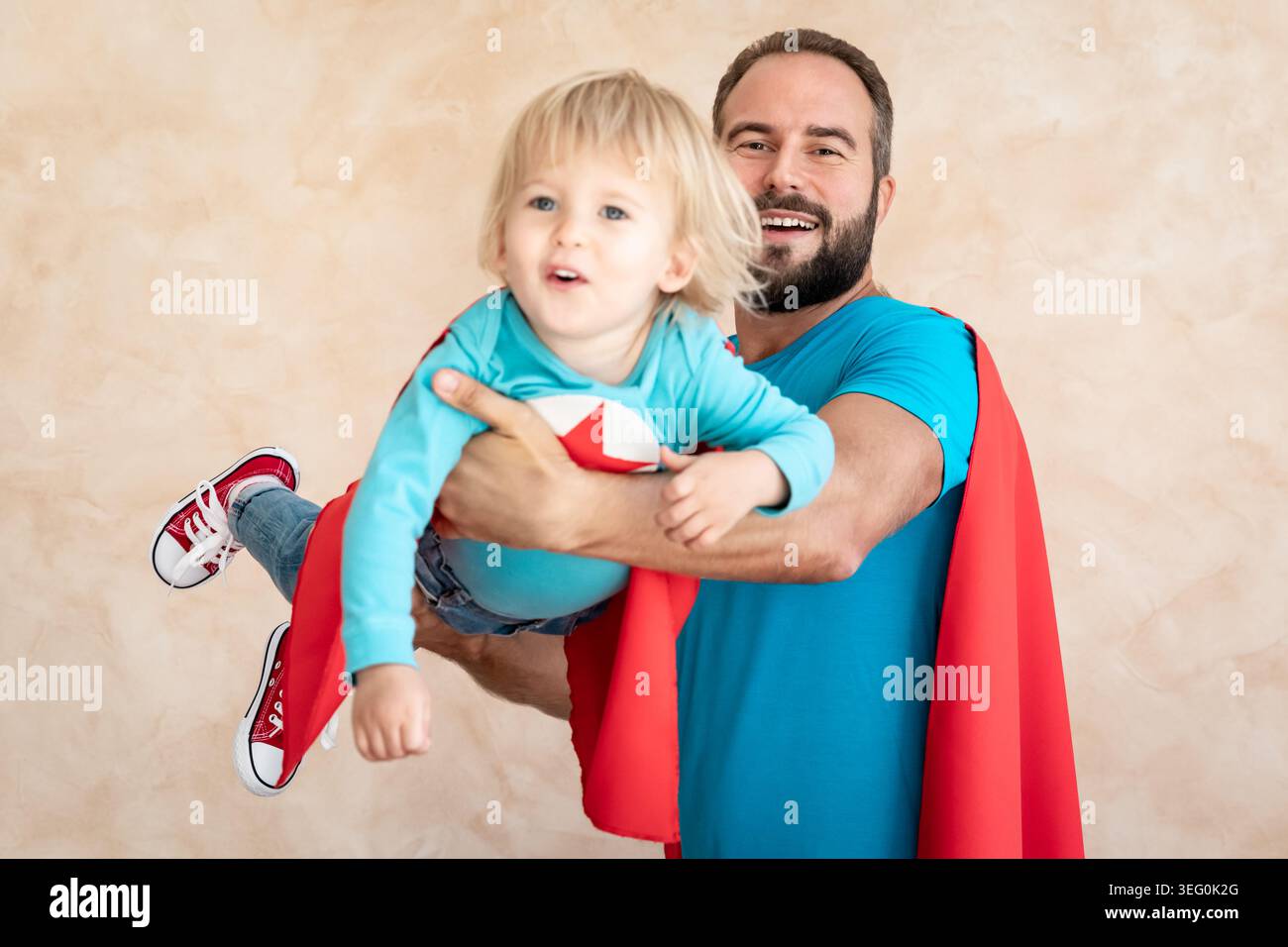 Un uomo e un bambino super eroe a casa. Padre e figlio supereroi che si divertono insieme. Concetto di vacanza in famiglia. Felice giornata di papà Foto Stock