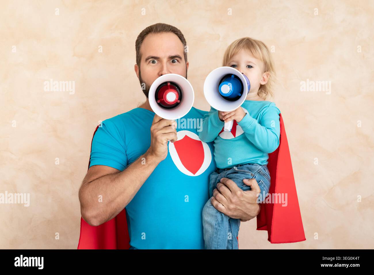 Un uomo e un bambino super eroe a casa. Padre e figlio supereroi che si divertono insieme. Concetto di vacanza in famiglia. Felice giornata di papà Foto Stock