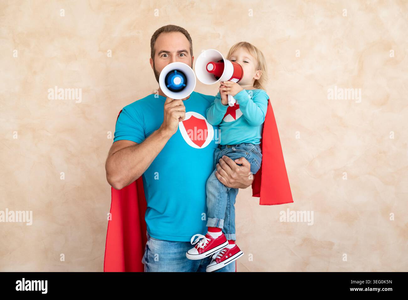 Un uomo e un bambino super eroe a casa. Padre e figlio supereroi che si divertono insieme. Concetto di vacanza in famiglia. Felice giornata di papà Foto Stock