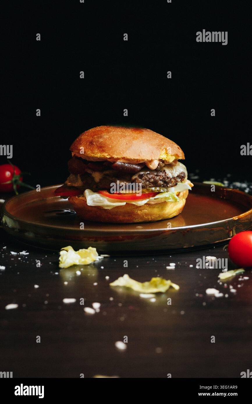 Lo sfondo scuro mostra l'hamburger su un piatto rotondo di legno Foto Stock
