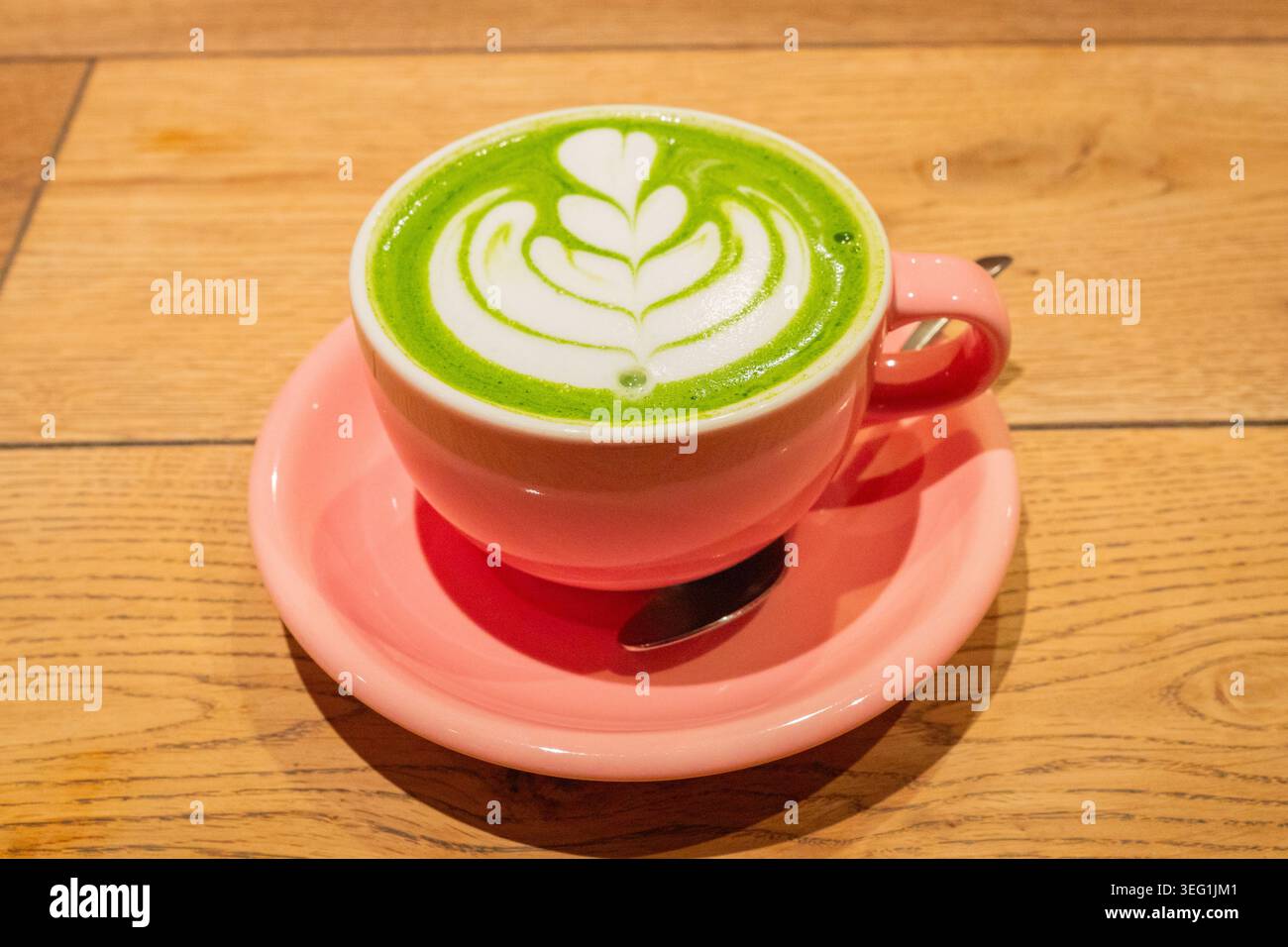 Tè verde matcha con decorazione floreale in schiuma in tazza porcellana rosa sul tavolo presso la caffetteria in Giappone. Foto Stock