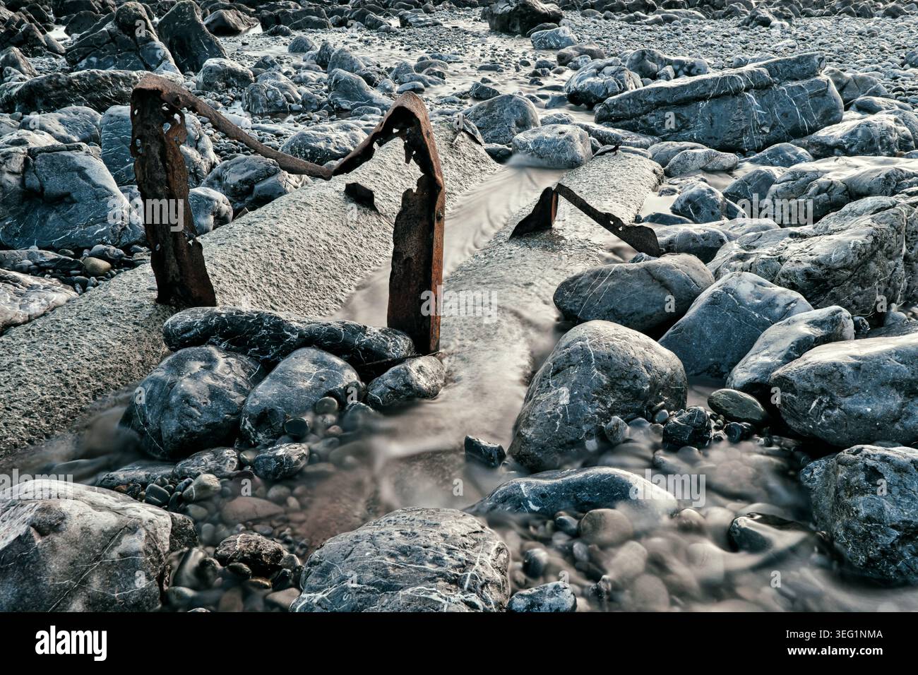 Canale d'acqua in cemento, metallo arrugginito e massi arrotondati a Middle Cove, Stackpole Quay. Foto Stock