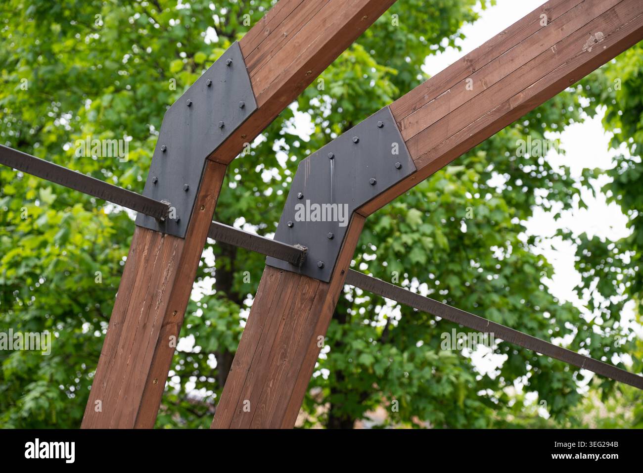 Piastre e staffe in metallo nero pesante che collegano spesse travi in legno di una struttura in legno da esterno o arco architettonico. Collegamento strutturale in acciaio Foto Stock