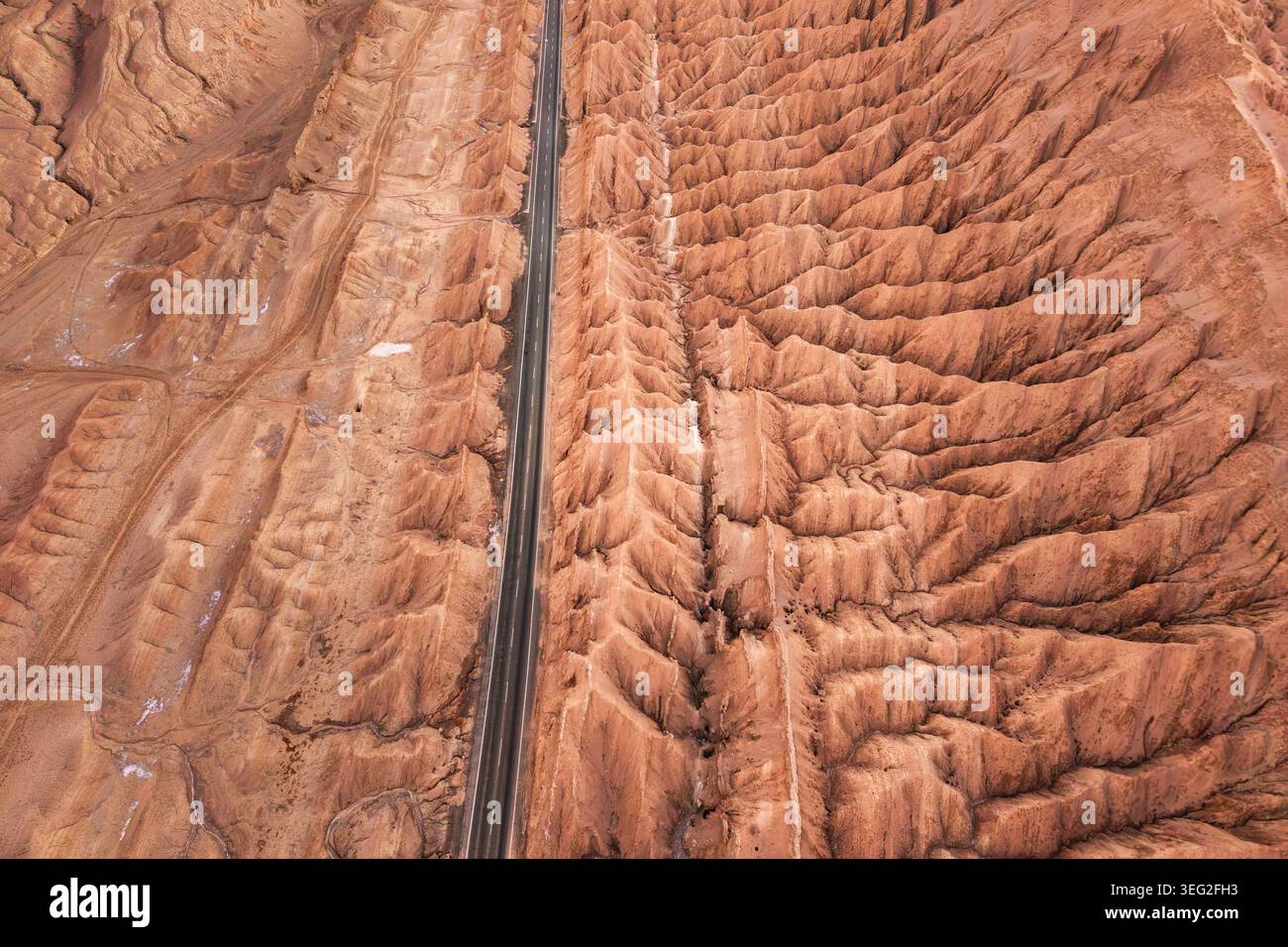 Vista in droni di un'autostrada asfaltata dritta che taglia attraverso aspre creste e canyon erosi nel deserto di Atacama, Cile, evidenziando un viaggio panoramico Foto Stock