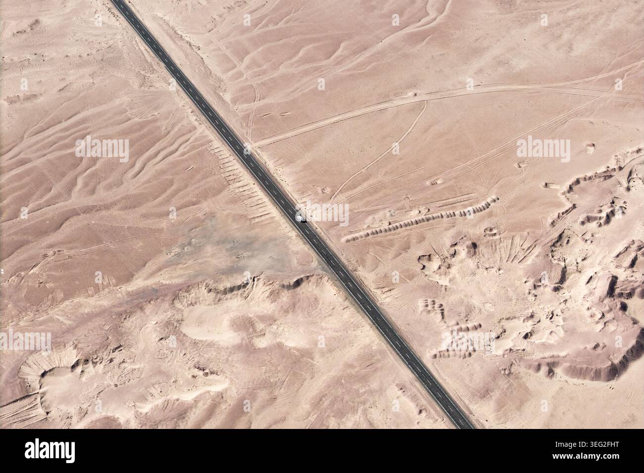 Vista aerea di una lunga autostrada asfaltata che attraversa il deserto di Atacama, in Cile, con dune di sabbia e terreno arido. Viaggio panoramico in auto in remoto Foto Stock