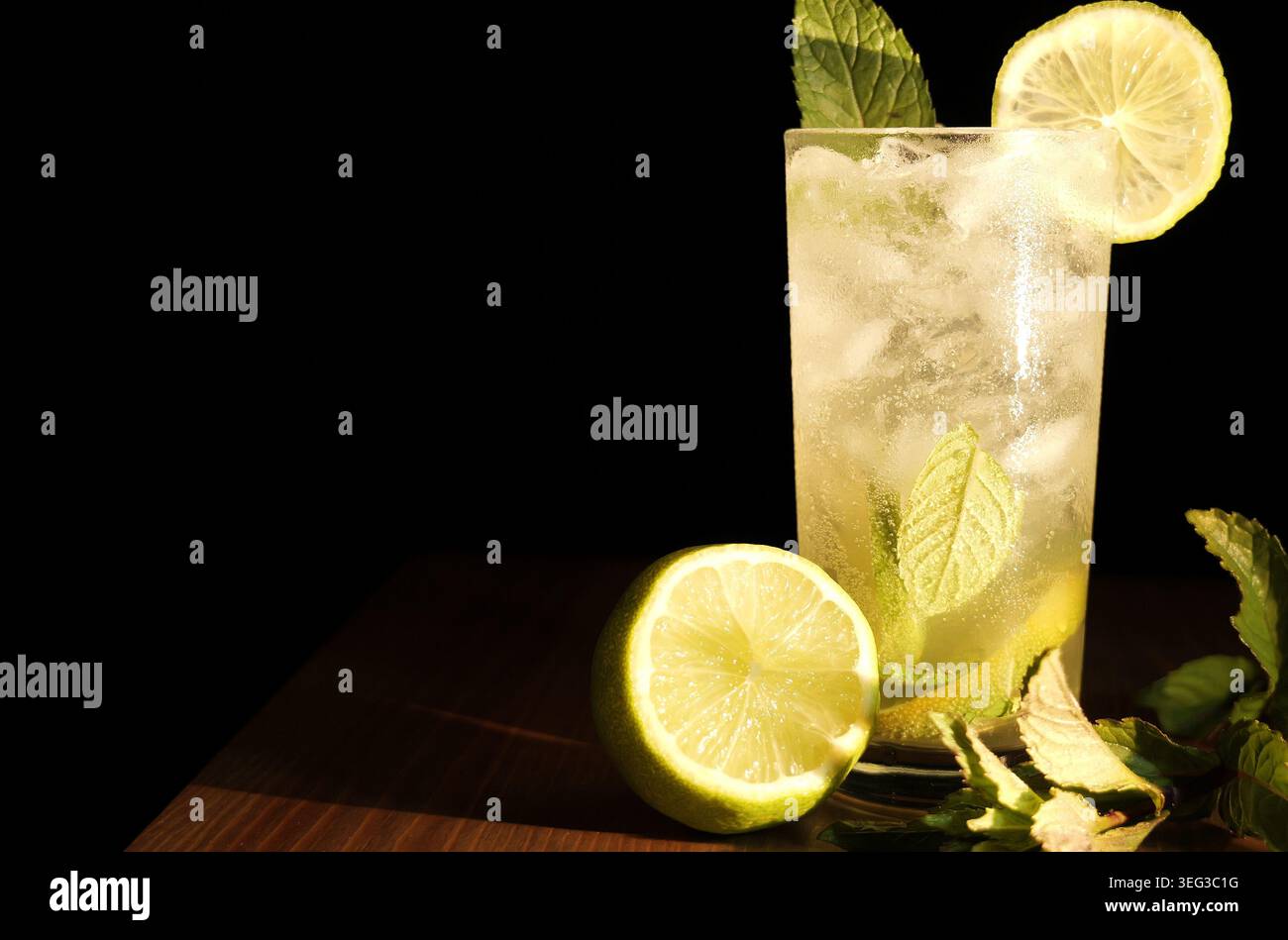 Il cocktail Mojito, caratterizzato da menta fangosa, spicchi di lime, ghiaccio e acqua soda, offre un'esperienza di bevande fresche, fresche e estive, perfetta per rilassarsi Foto Stock