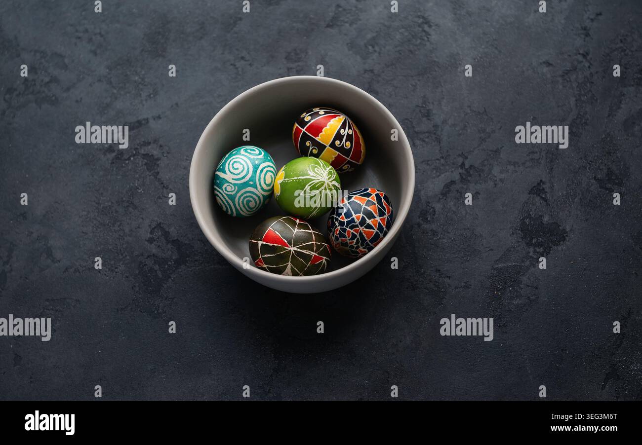 Cinque tradizionali uova di Pasqua Pysanky ucraine con motivi geometrici e floreali in una ciotola grigia. Vista dall'alto verso il basso delle uova pisanky ucraine dipinte a mano. Foto Stock