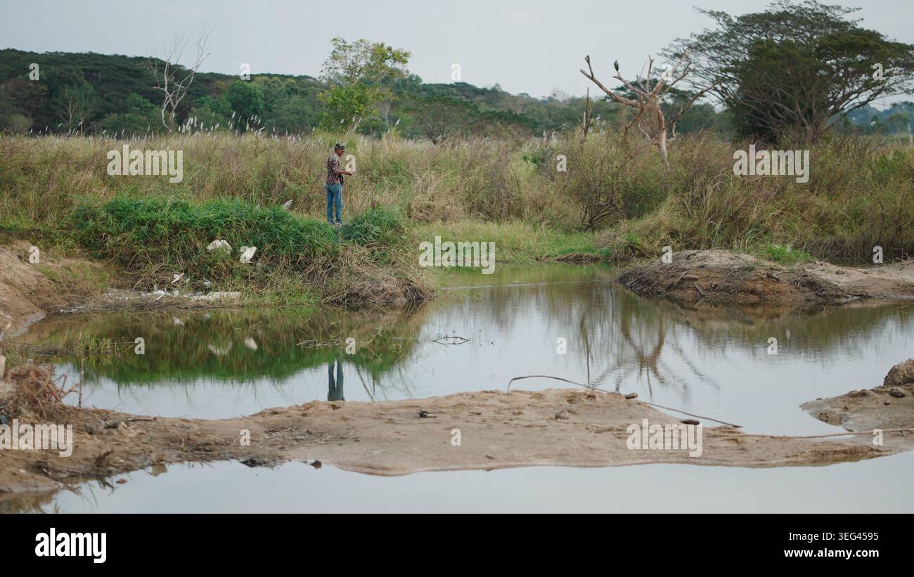 Uomo che pesca in un paesaggio naturale rurale e che ama le attività ricreative all'aperto Foto Stock