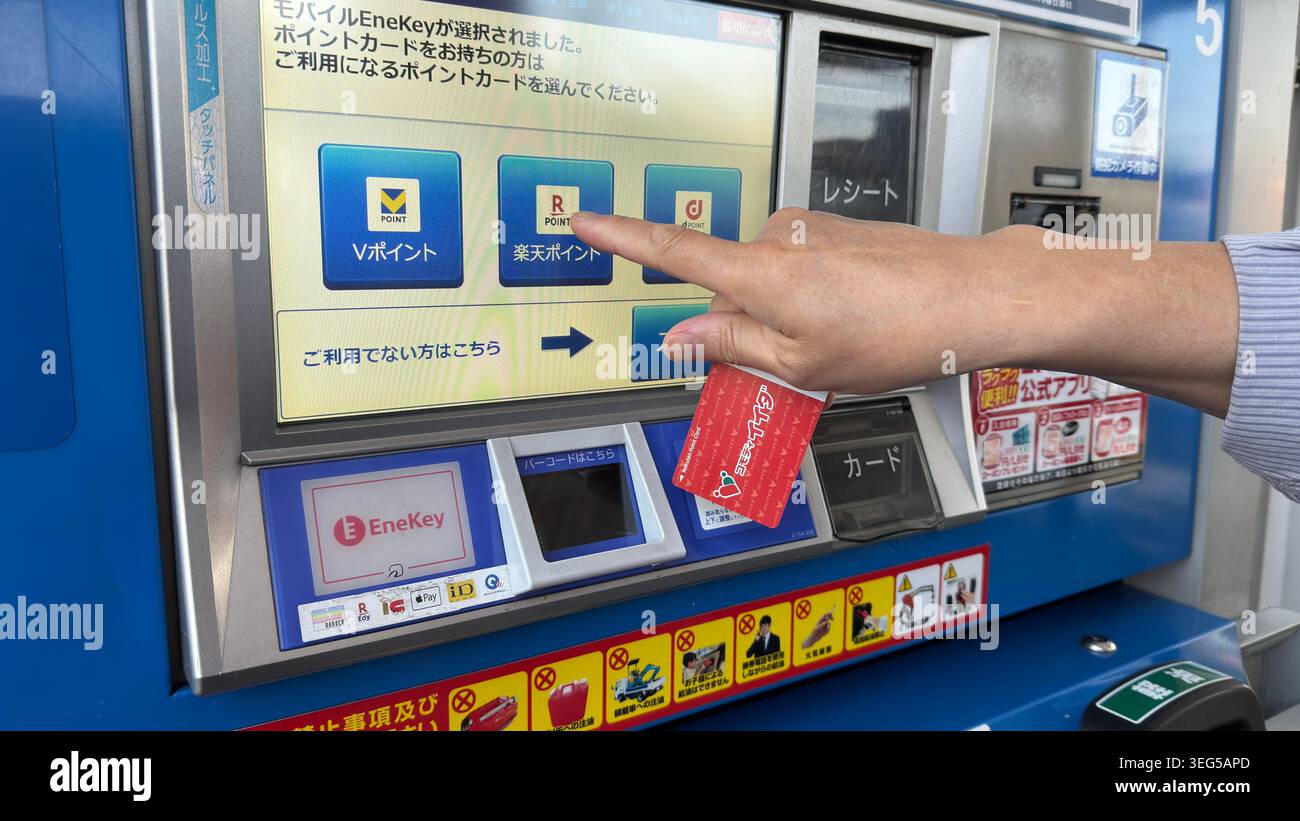 Un cliente si rivolge all'opzione Rakuten Point su uno schermo self-service del distributore di carburante tenendo una scheda puntiforme presso una stazione ENEOS EneJet. Foto Stock