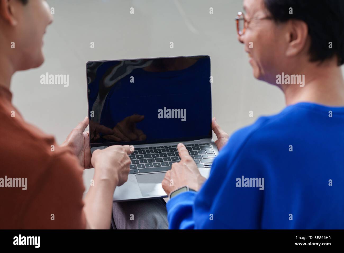 Uomo asiatico che insegna agli anziani come usare il laptop, l'apprendimento digitale intergenerazionale Foto Stock