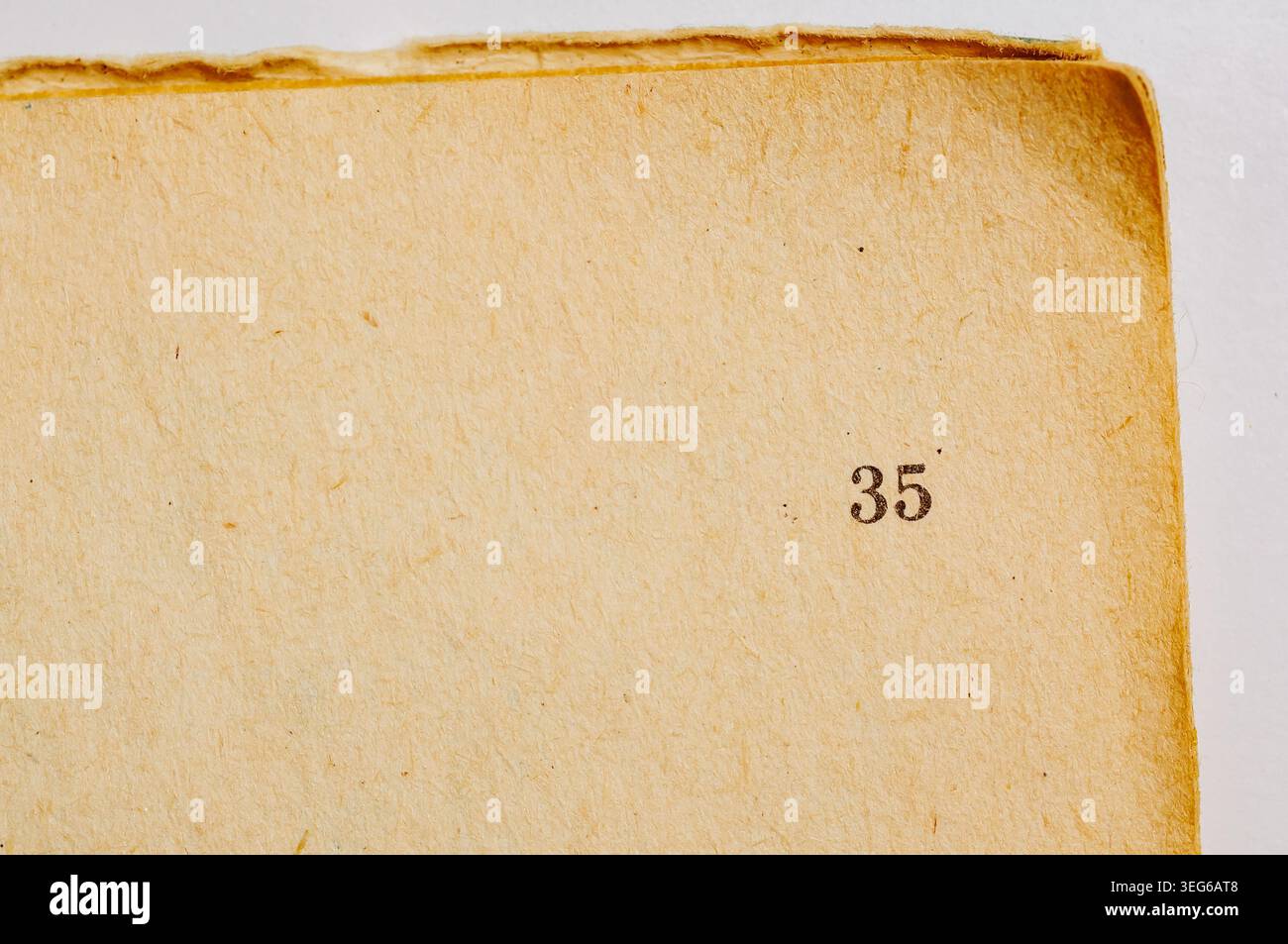 Una pagina ingiallita e testurizzata di un vecchio libro mostra il numero 35 in inchiostro scuro, evidenziando il passaggio del tempo e della storia Foto Stock