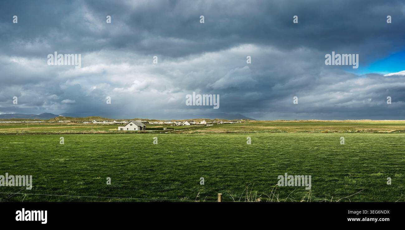 Ampio paesaggio della campagna di Kerry caratterizzato da un pascolo illuminato dal sole e pesanti nuvole di pioggia sulla costa. Foto Stock