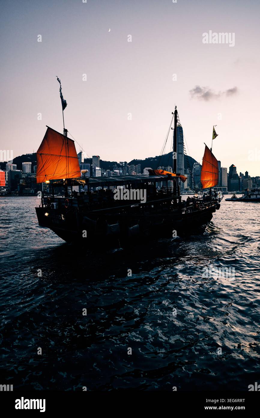 Barca a vela rossa Aqua Luna sul Victoria Harbour al crepuscolo Foto Stock