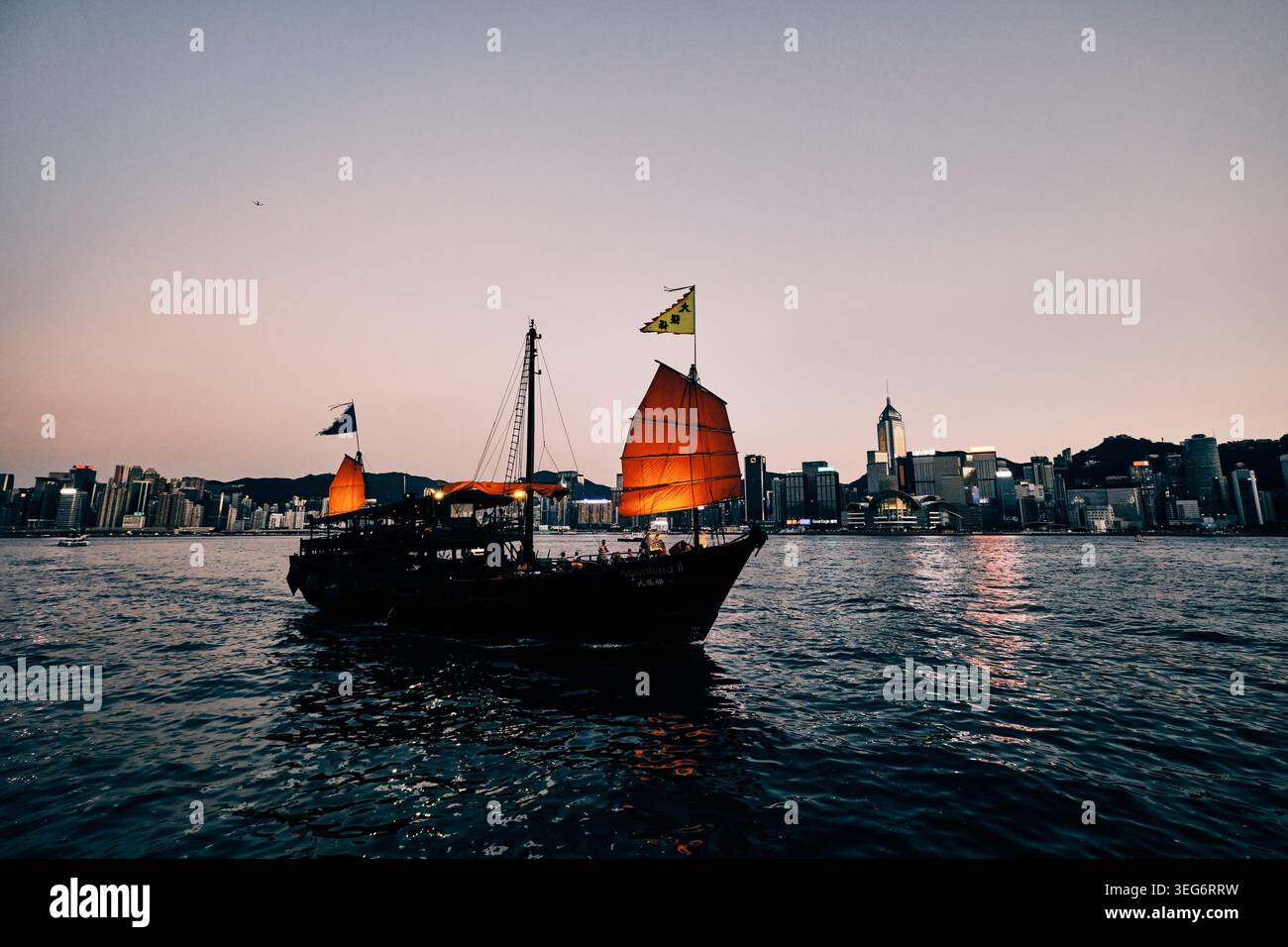 Barca a vela rossa qua Luna con giunca a vela nel porto Victoria al tramonto Foto Stock
