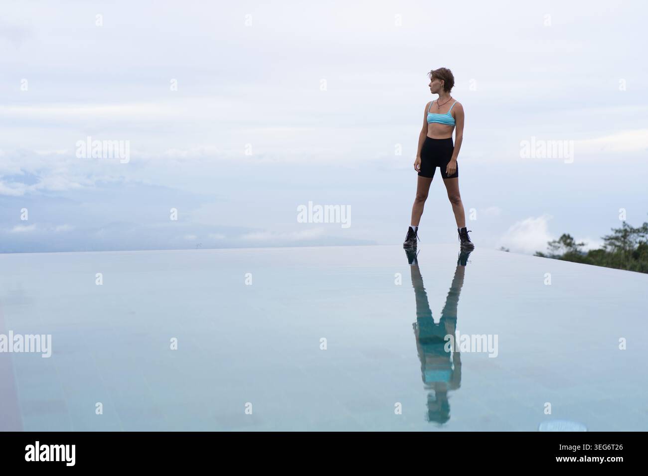 Donna sportiva che guarda l'orizzonte dall'infinity pool edge, Munduk, Bali Foto Stock