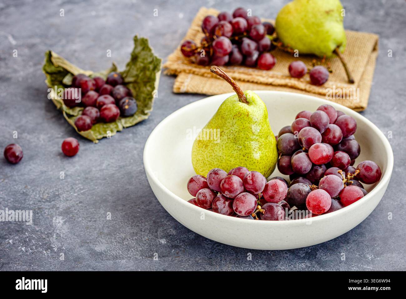 Pere fresche e uva rossa disposte in un recipiente di ceramica Foto Stock