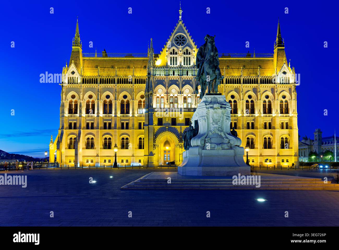 Budapest mette in mostra il suo edificio del Parlamento con luci luminose di notte. Di fronte si erge una statua che si aggiunge alla scena storica della città. Foto Stock