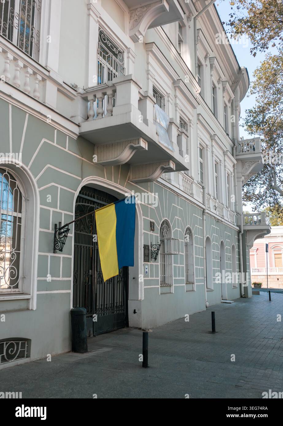 La bandiera Ucraina è appesa all'ingresso di un edificio in stile classico con finestre ad arco e balconi nel centro di Odesa Foto Stock