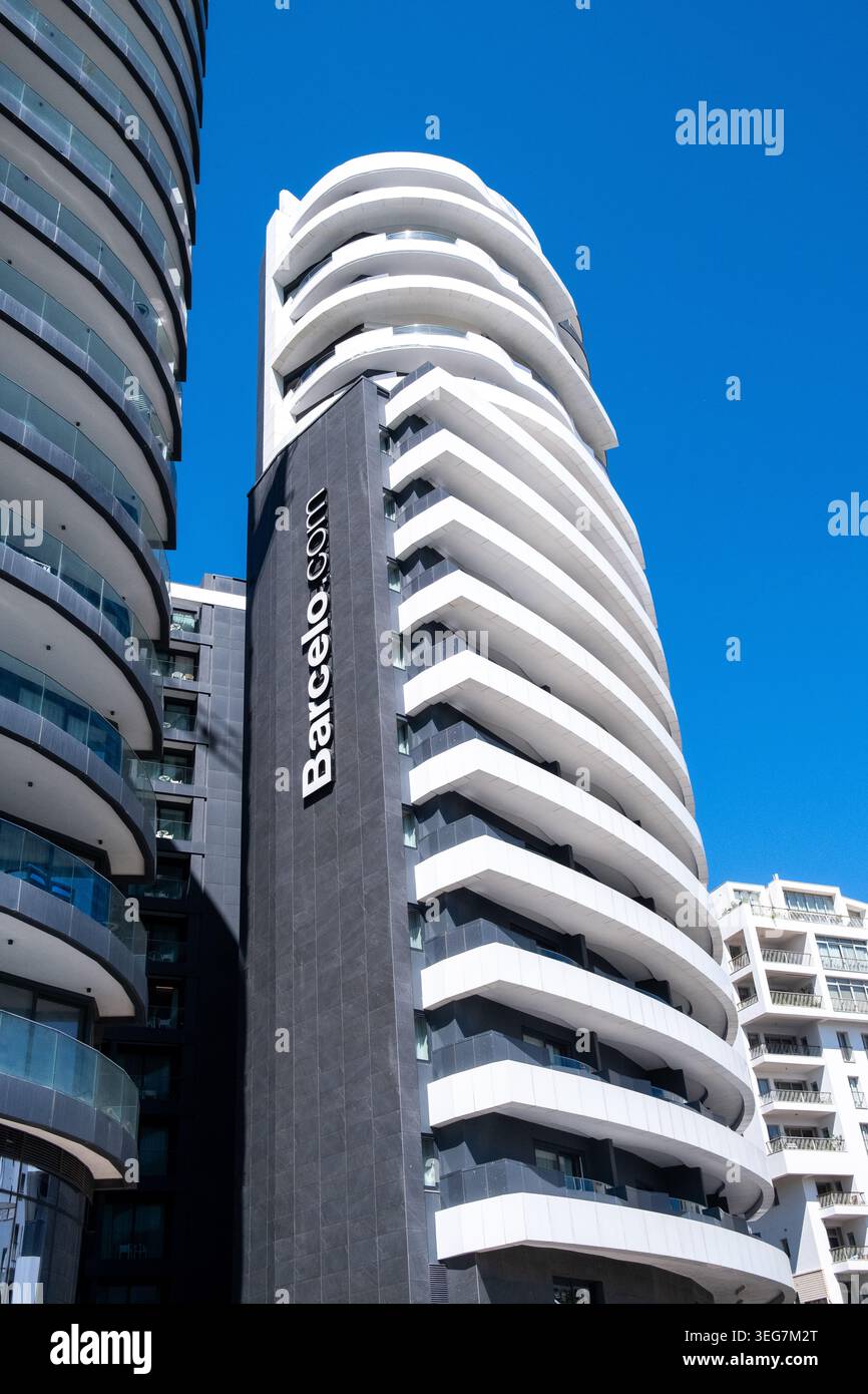 Vista ad angolo basso dei moderni e alti edifici di appartamenti con balconi sovrapposti, facciate curve e un cielo azzurro limpido a Sliema, Malta, 5 agosto 2025. TH Foto Stock