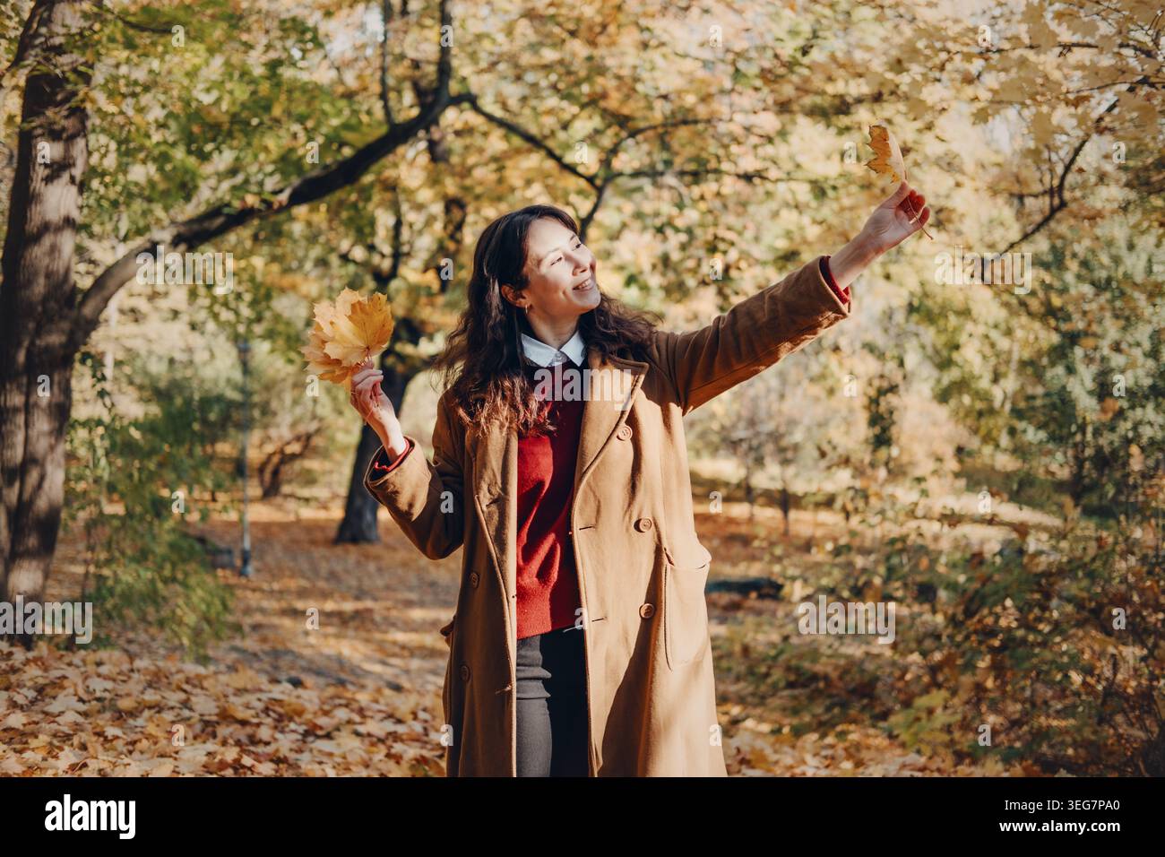 La donna si trova tra gli alberi alti nella foresta autunnale. Il benessere mentale del bagno nella foresta, riducendo lo stress e l'ansia, migliorando il benessere emotivo. Foto Stock