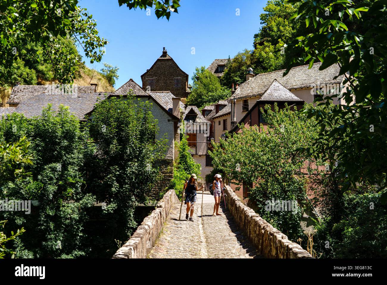 Francia. Aveyron (12). Conques-en-Rouergue. Sulla via Podiensis. La via di San Giacomo di Compostela. I pellegrini che attraversano il ponte sul Dourdou, lo sanno Foto Stock