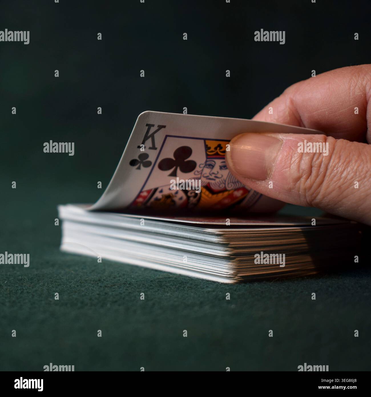 Una carta da gioco King of Clubs è rappresentata in modo preminente, rivolta verso l'alto, su uno sfondo di feltro verde scuro. Foto Stock
