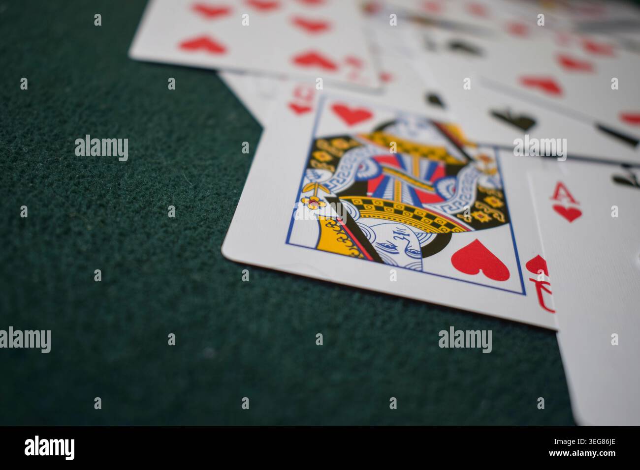 Vista dettagliata di una carta da gioco della Regina di cuori, rivolta verso l'alto, su una superficie verde in feltro. Foto Stock
