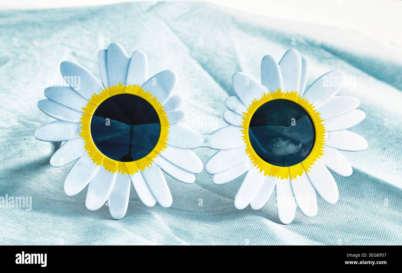 Occhiali da sole da festa a tema girasole su una superficie bianca Foto Stock