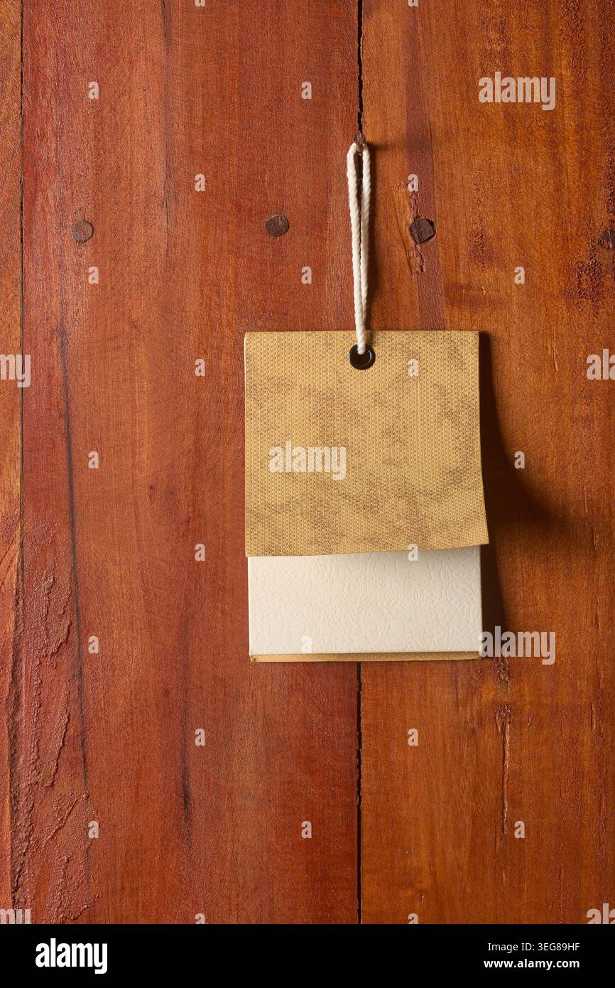 cartellino di carta rettangolare vuoto sulla superficie della tavola di legno marrone, cordoncino bianco appeso al chiodo, spazio di copia del modello di mockup del prezzo di vendita al dettaglio Foto Stock