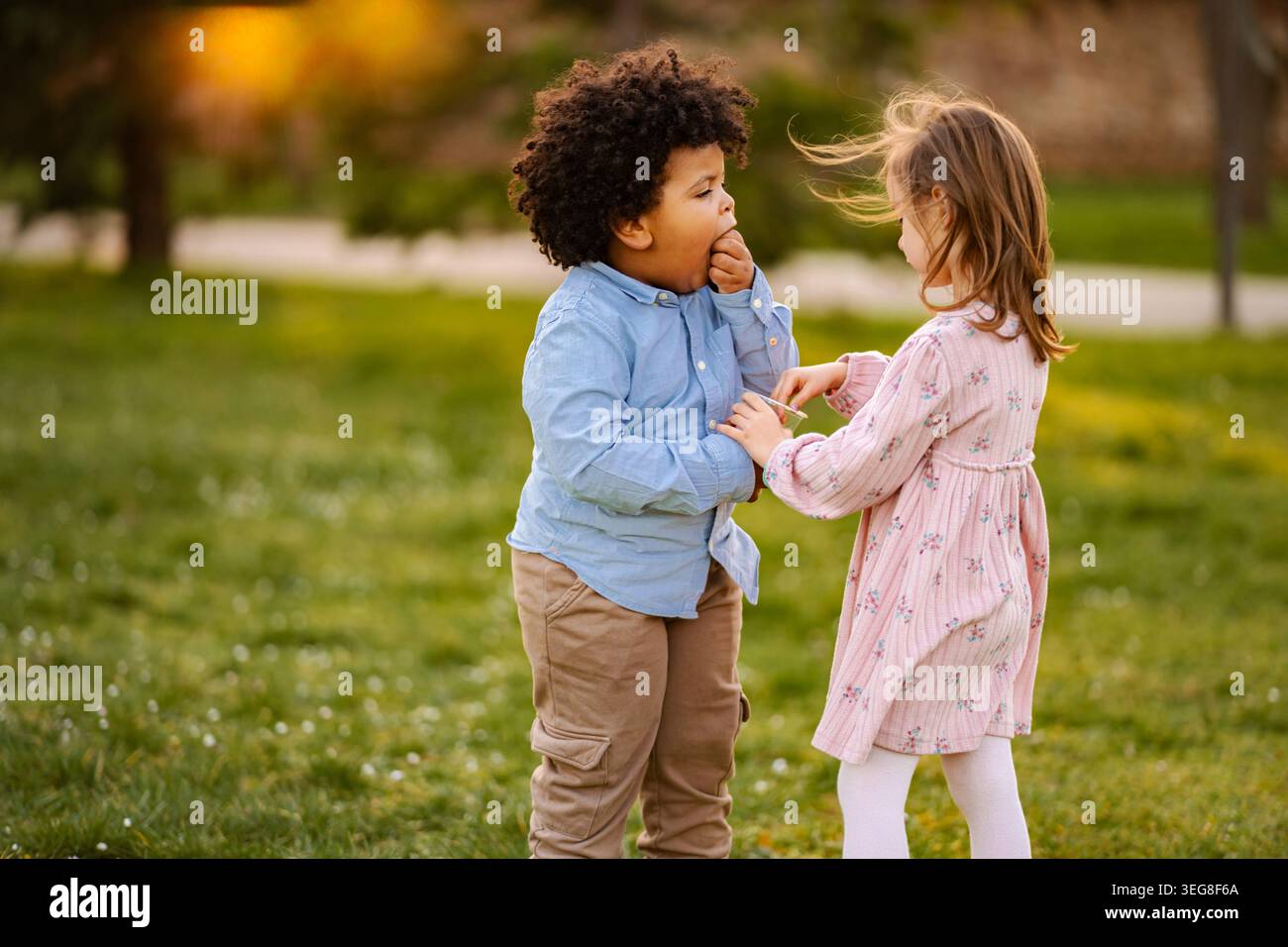 Diversi bambini che condividono uno spuntino e divertono nel parco all'aperto Foto Stock
