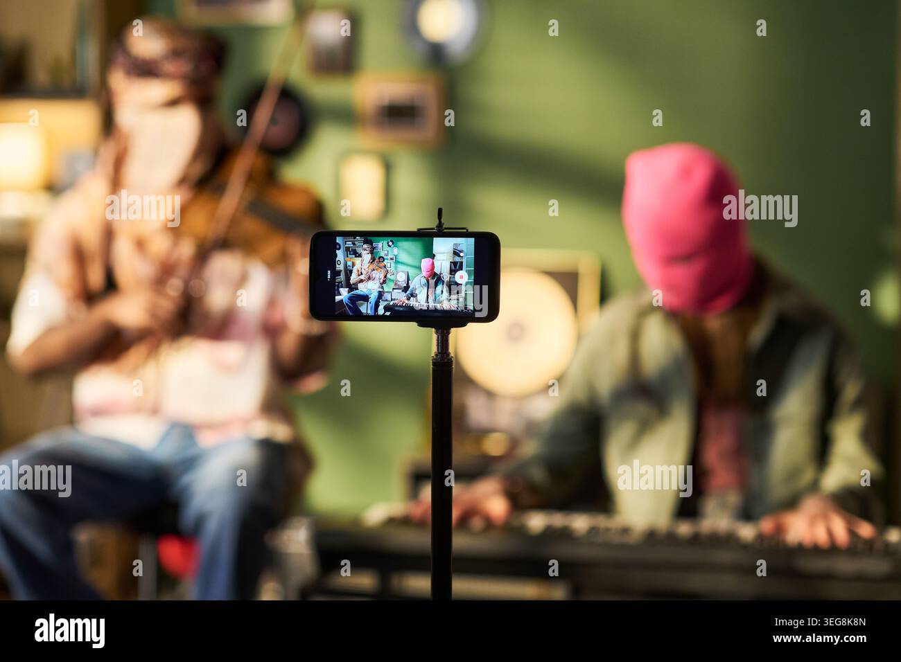 Giovani musicisti mascherati che si esibiscono durante la registrazione di video sullo smartphone Foto Stock