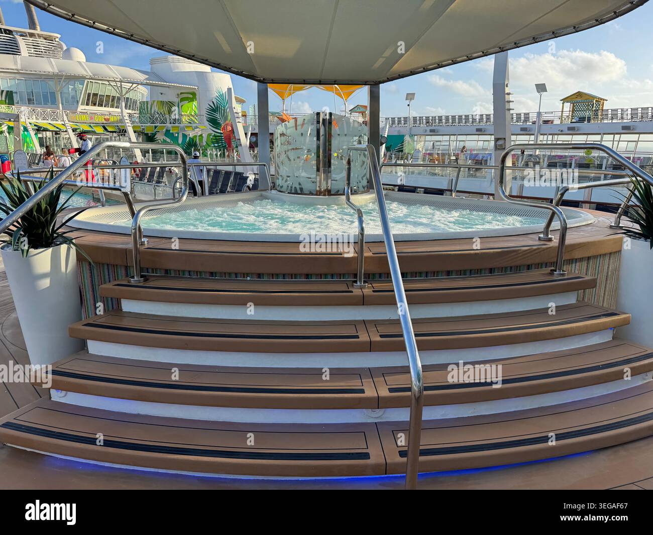 Grande vasca idromassaggio Jacuzzi con scale e ringhiere in acciaio inox su una terrazza esterna sotto un baldacchino. Foto Stock