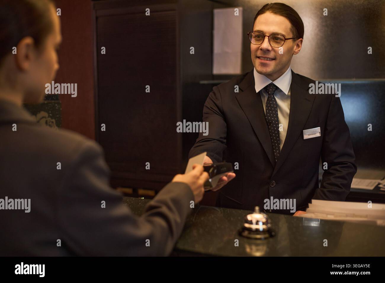 Il giovane receptionist dell'hotel consegna la tessera chiave agli ospiti Foto Stock