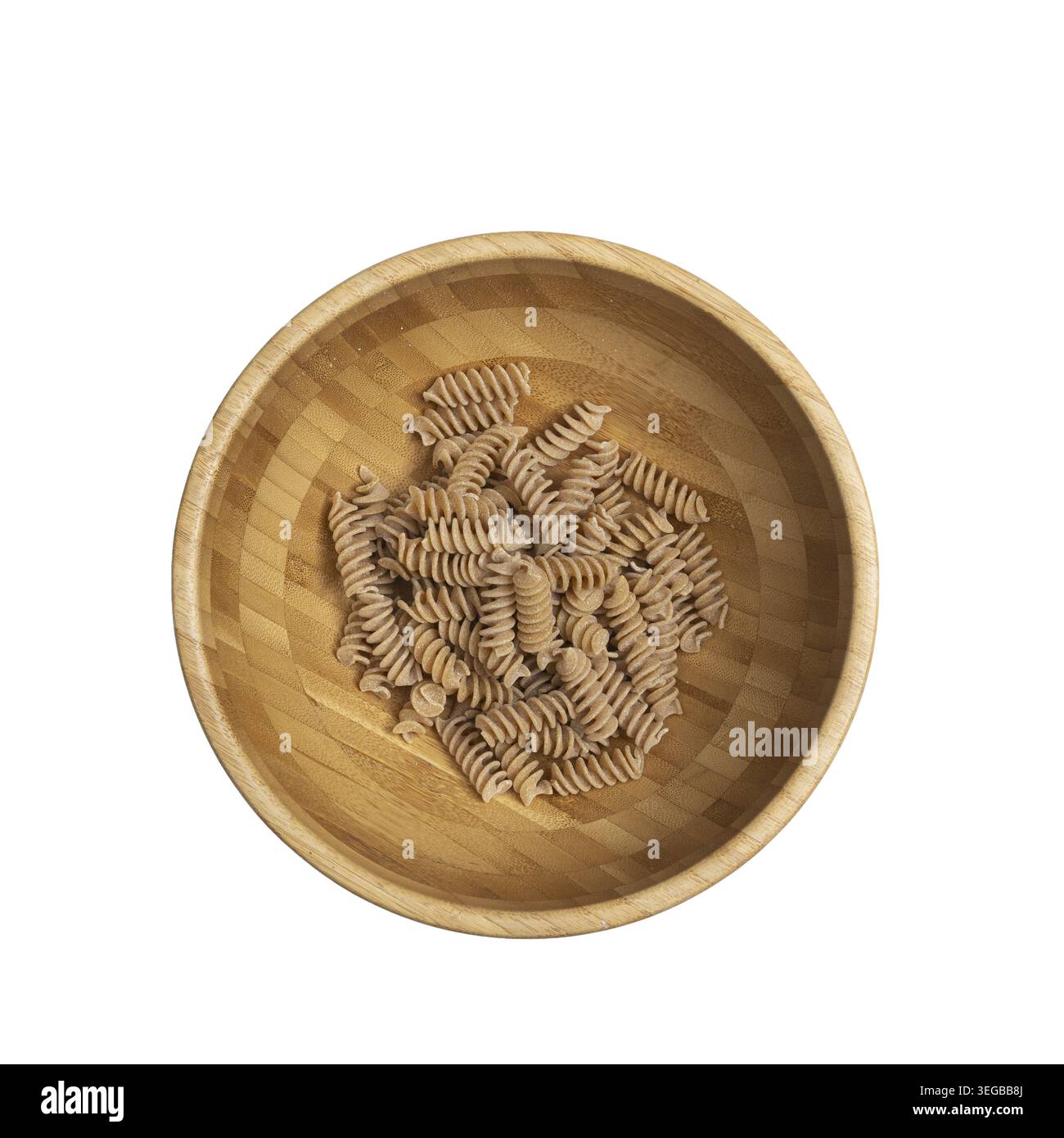 Fusilli di frumento intero in un recipiente di legno su una superficie trasparente Foto Stock
