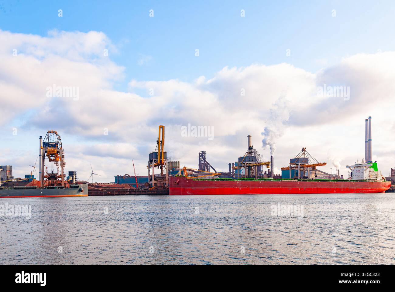 Nave portarinfuse di grandi dimensioni attraccata al terminal portuale industriale con gru cargo e camini di fabbrica a eemshaven, nei paesi bassi Foto Stock