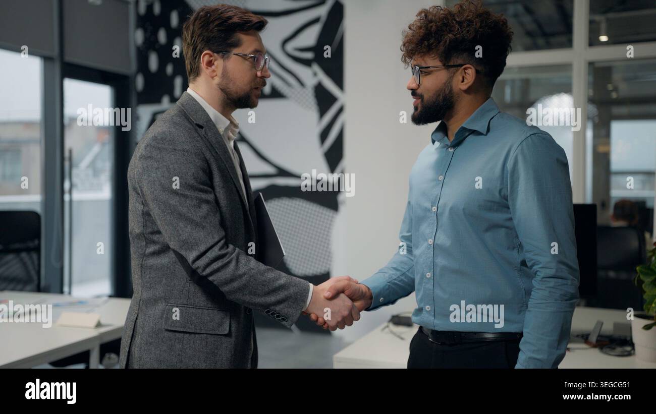 Due uomini di diversità stringono la mano nell'ufficio aziendale lavoro di squadra collaborazione gesti lavoro di successo accordo approvato due uomini multietnici scuotono Foto Stock