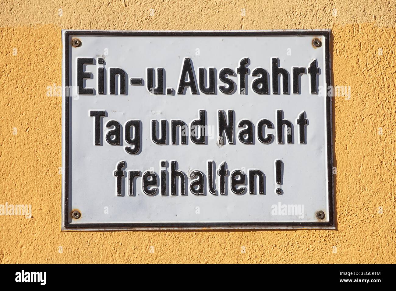 Schild Einfahrt und Ausfahrt Tag und Nacht freihalten an einer gelben Mauer, Deutschland Foto Stock