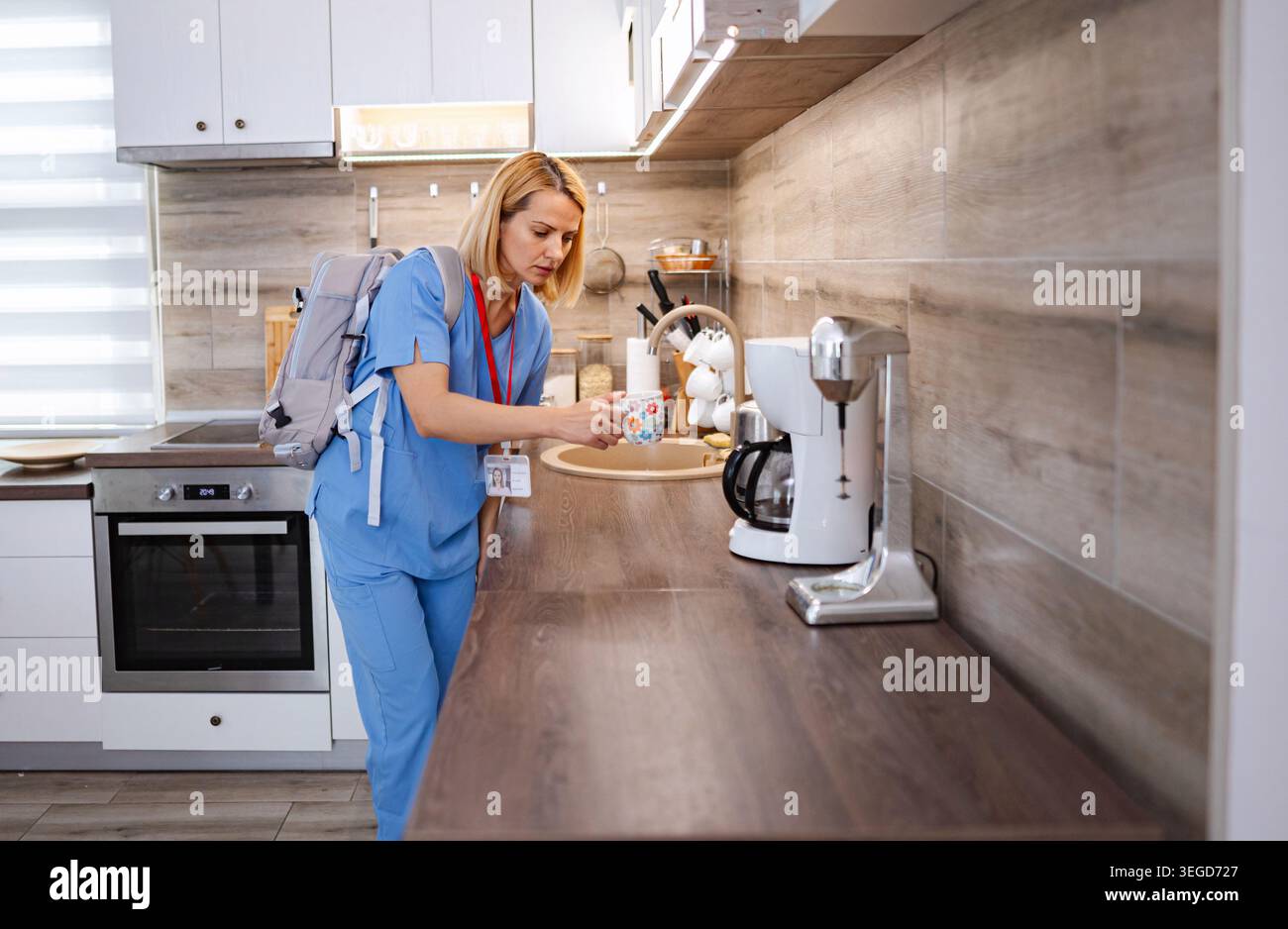 Infermiera che prepara il caffè in cucina prima del turno di lavoro Foto Stock
