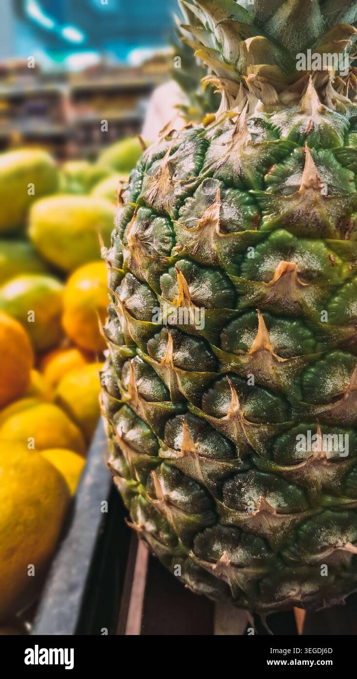 Trovare l'ananas perfetto in un negozio locale significa controllare il colore, il peso e l'aroma. Cerca la pelle dorata, foglie verdi che si estraggono facilmente Foto Stock