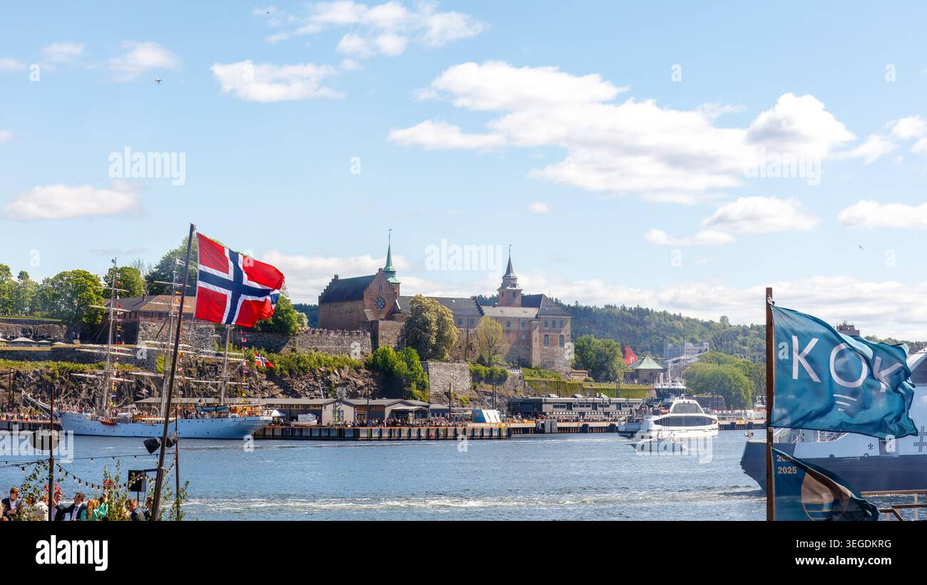 Oslo, Norvegia - 17 maggio 2025: Bandiere norvegesi che sventolano lungo il lungomare con la fortezza di Akershus e viste festose del porto durante il giorno della Costituzione Foto Stock